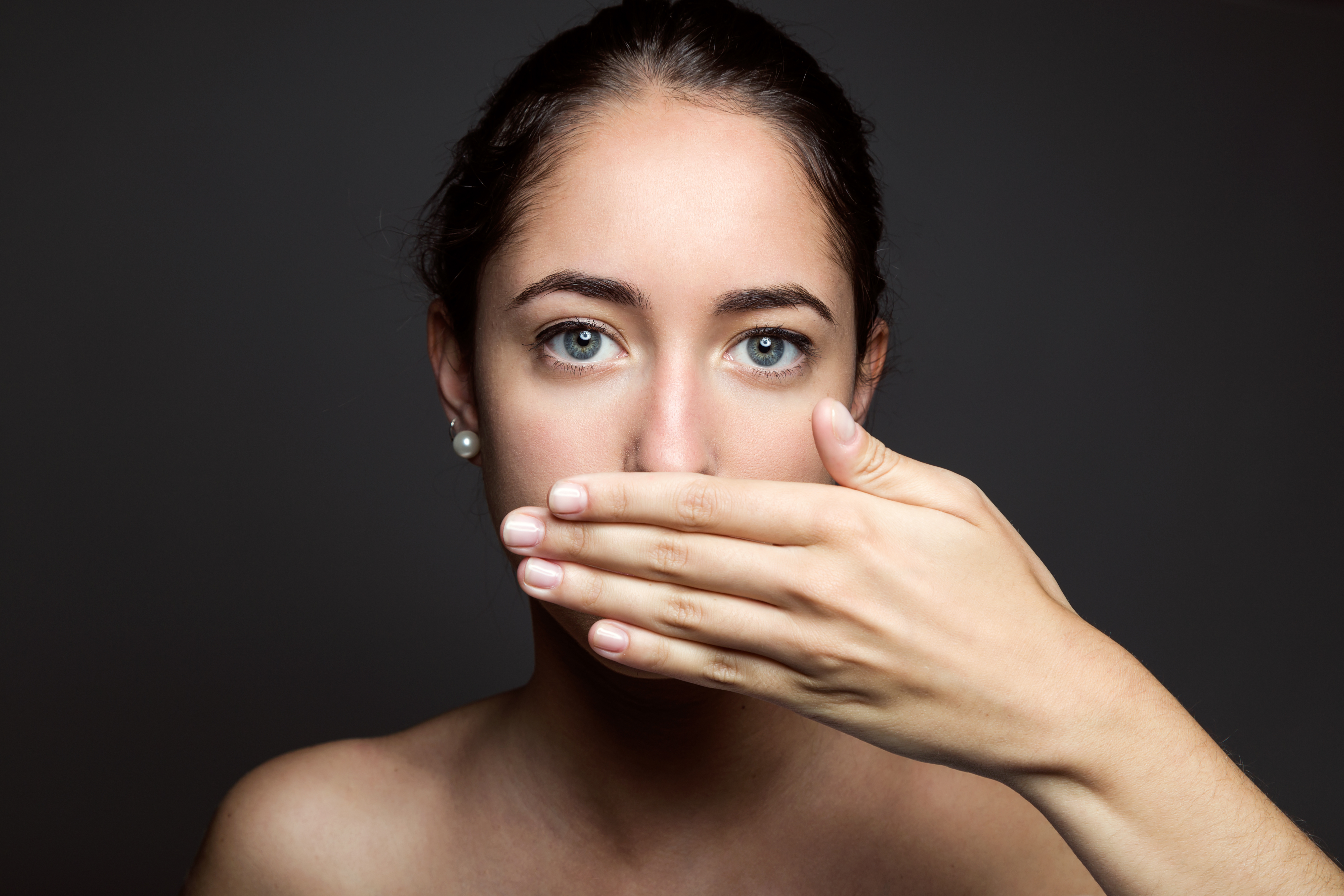 Portrait Of Beautiful Young Woman Covering Her Mouth With Hand. Isolated.