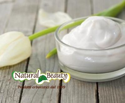Vasetto ripieno di crema cosmetica naturale su una tavola di legno con accanto un fiore bianco