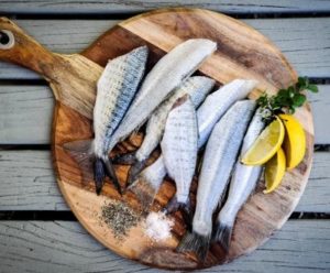 Tagliere con del pesce fresco appena pulito e pronto per la cottura