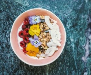 Ciotola di yogurt arricchito con frutti rossi, cereali e cocco